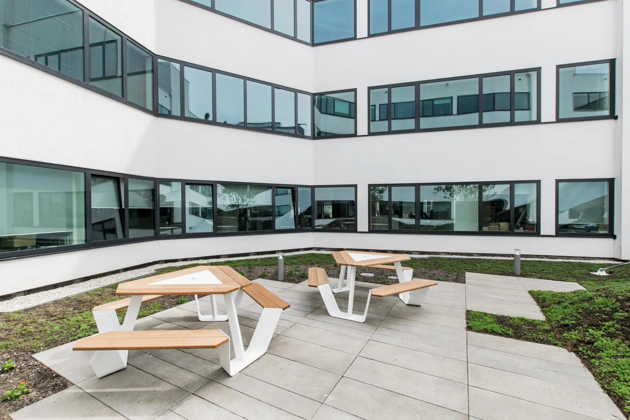 Binnenplaats met moderne picknicktafels en een omliggend wit kantoorgebouw aan de Grote Marktstraat.
